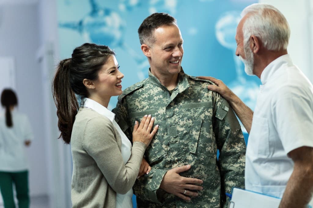 Veteran and spouse in consultation with a care professional—respectful, veteran-focused setting for ANS and recovery care.